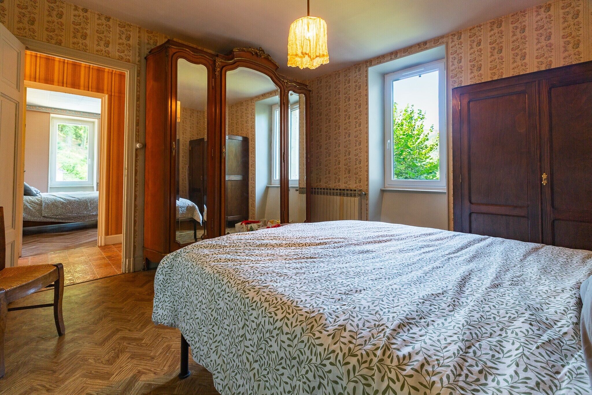 Une chambre à coucher avec un lit, une chaise, une armoire et un miroir.
