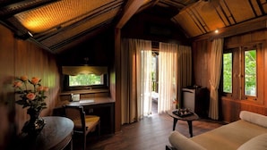 Una habitación con una cama, un escritorio, una silla, una mesita y una ventana con cortinas.