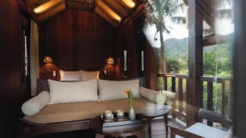 Una habitación de madera con un sofá, una mesita con una bandeja de objetos y vistas al exterior.