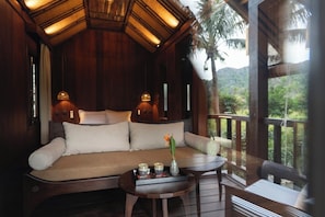 Una habitación de madera con un sofá, una mesita con una bandeja de objetos y vistas al exterior.