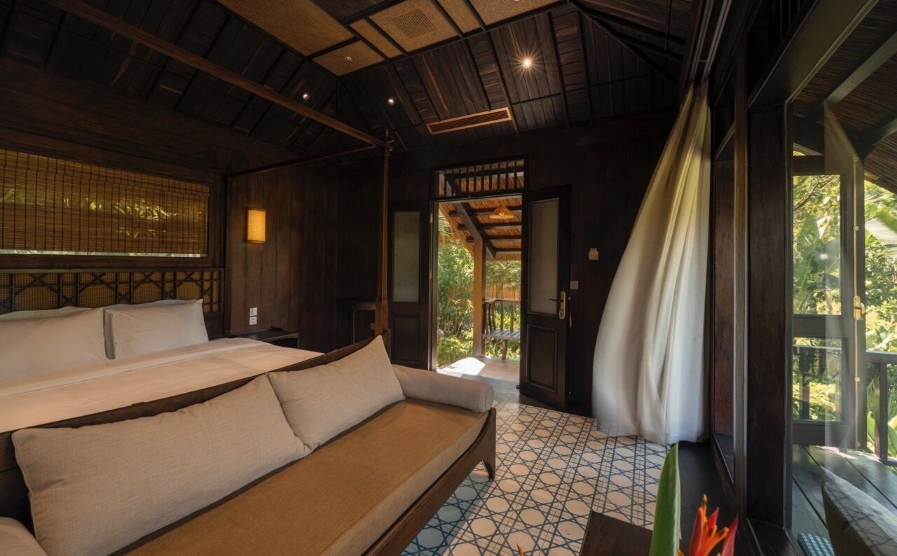 Habitación tradicional con cama, sofá y vistas al exterior.