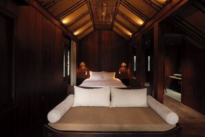 A large bed with a headboard, two bedside tables, and a ceiling with wooden beams and recessed lighting.