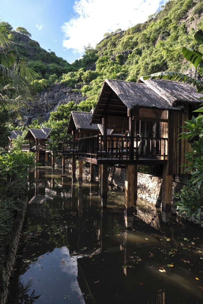 Bungalows sobre el agua con barandas de madera y una masa de agua tranquila al frente.