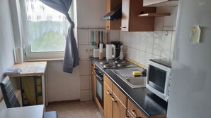 Eine kompakte Küche mit Holzausbau, einer Mikrowelle, einem Herd und einem Kühlschrank.