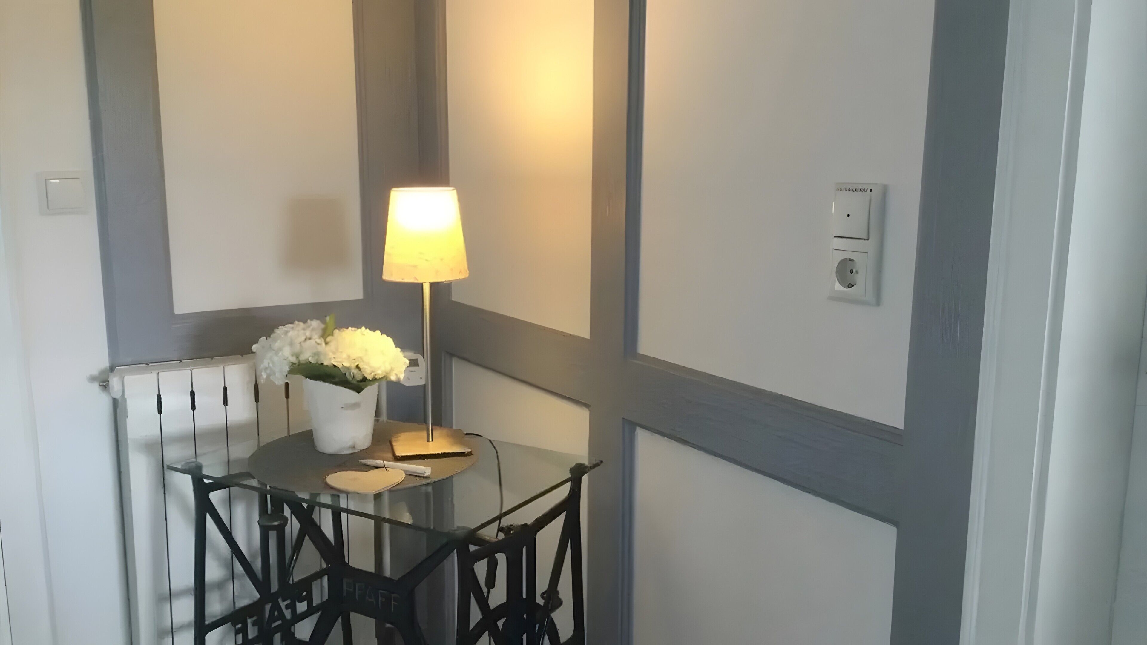 Una habitación con una mesa, sillas, una lámpara y un radiador.