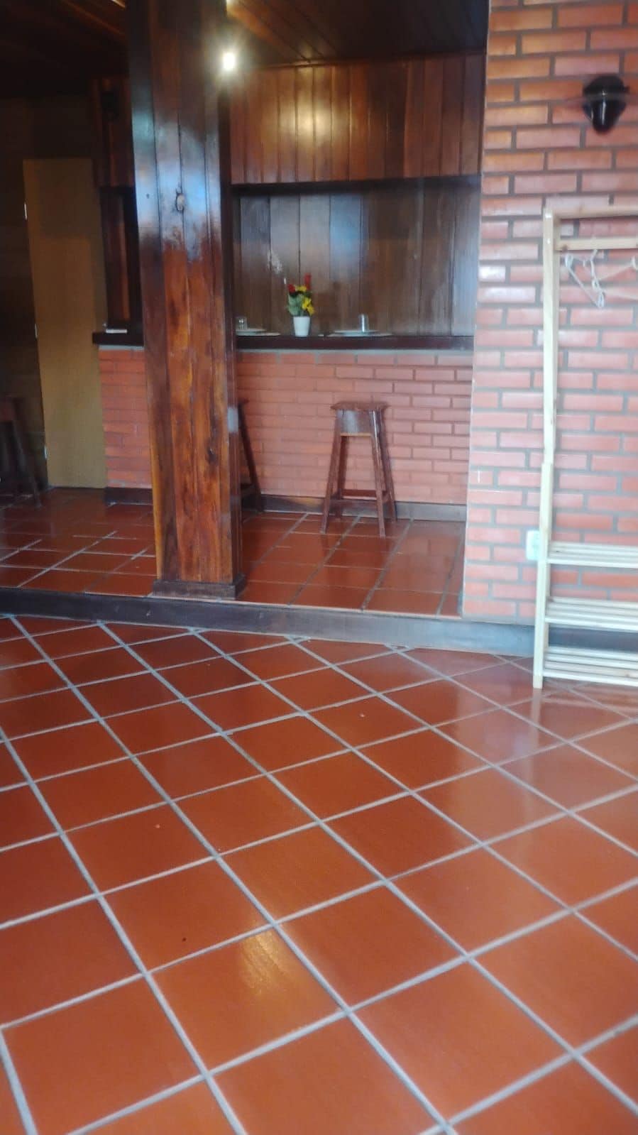 A room with a tiled floor, a wooden door, a brick wall, and a small stool.