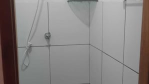 A small, tiled shower area with a glass shelf and a handheld showerhead. - Chale Zafira (Tibau do Sul)