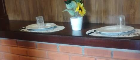 A bar area with two stools, a wooden counter, and a brick wall.