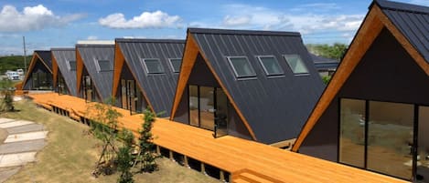 Une rangée de cabanes modernes, dotées de toits triangulaires, de grandes fenêtres et de terrasses en bois.
