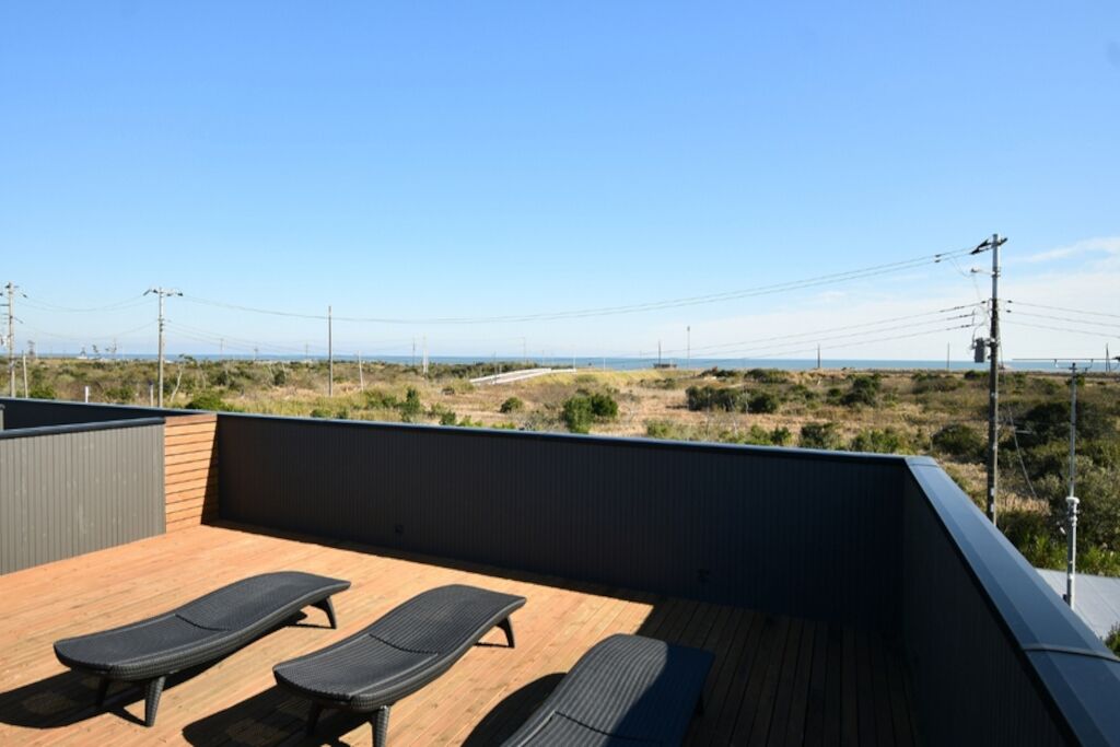 A rooftop deck with two lounge chairs, a view of the landscape, and power lines in the distance.