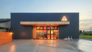 Un edificio moderno con una entrada amplia, puertas de vidrio y un alero de madera.