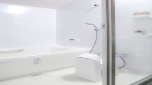 Un baño moderno con una bañera blanca, cabina de ducha de vidrio y un estante pequeño con artículos de aseo.