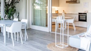 Uma sala de estar moderna com sofá, uma mesa de jantar com cadeiras e uma área de cozinha com fogão e armários.