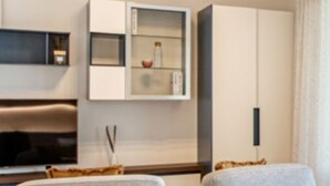 Uma sala de estar moderna com um sofá, uma televisão, um armário e uma TV de tela plana fixada na parede.