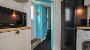 Una cocina compacta con microondas, un refrigerador negro y una lavadora.