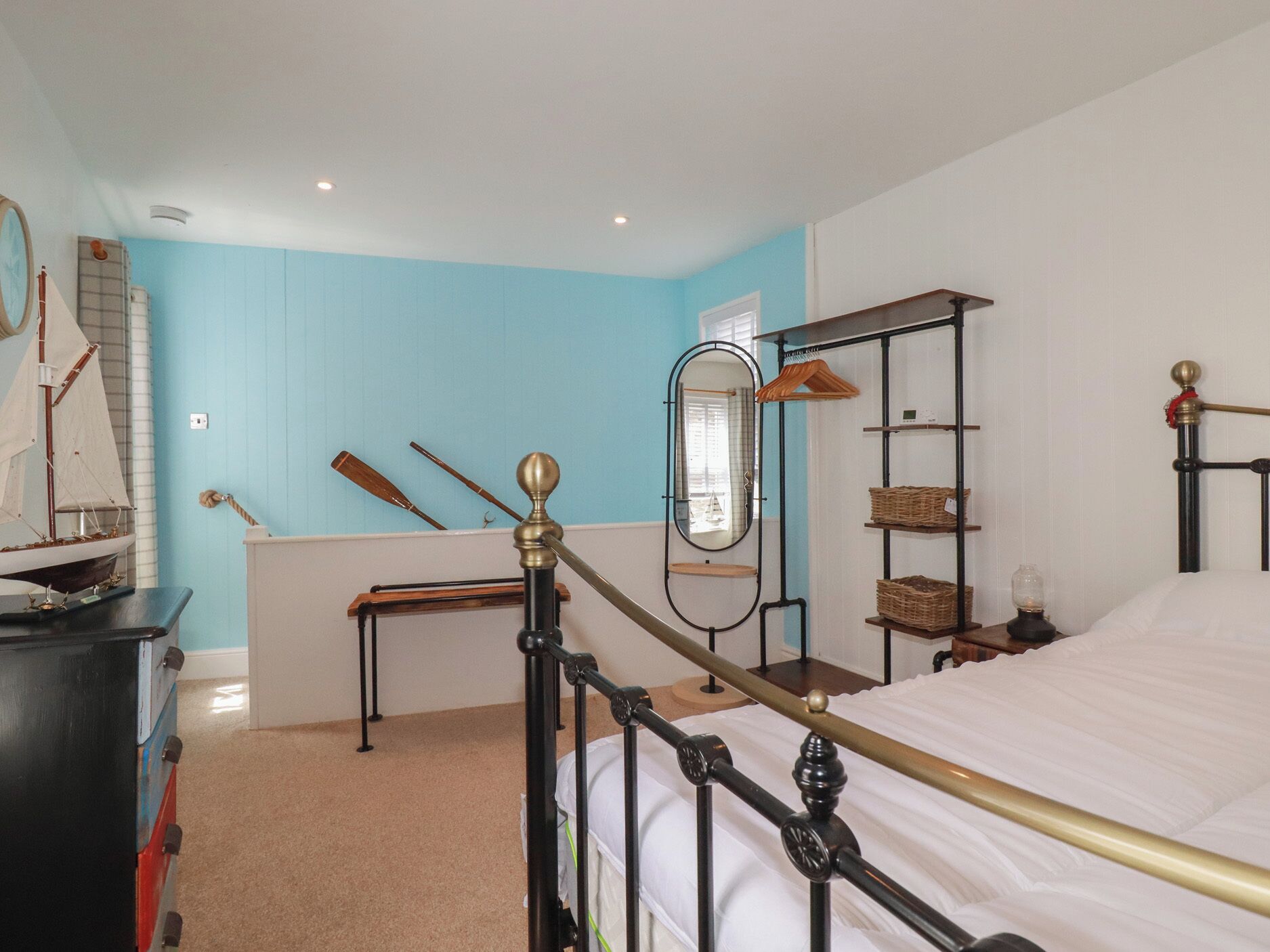 Un dormitorio con cama, cómoda, espejo y repisas con cestas.
