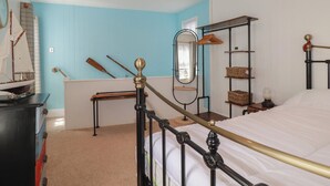Un dormitorio con cama, cómoda, espejo y repisas con cestas.