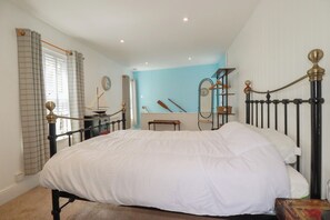 A bedroom with a large bed, a dresser, a mirror, and a window with curtains.
