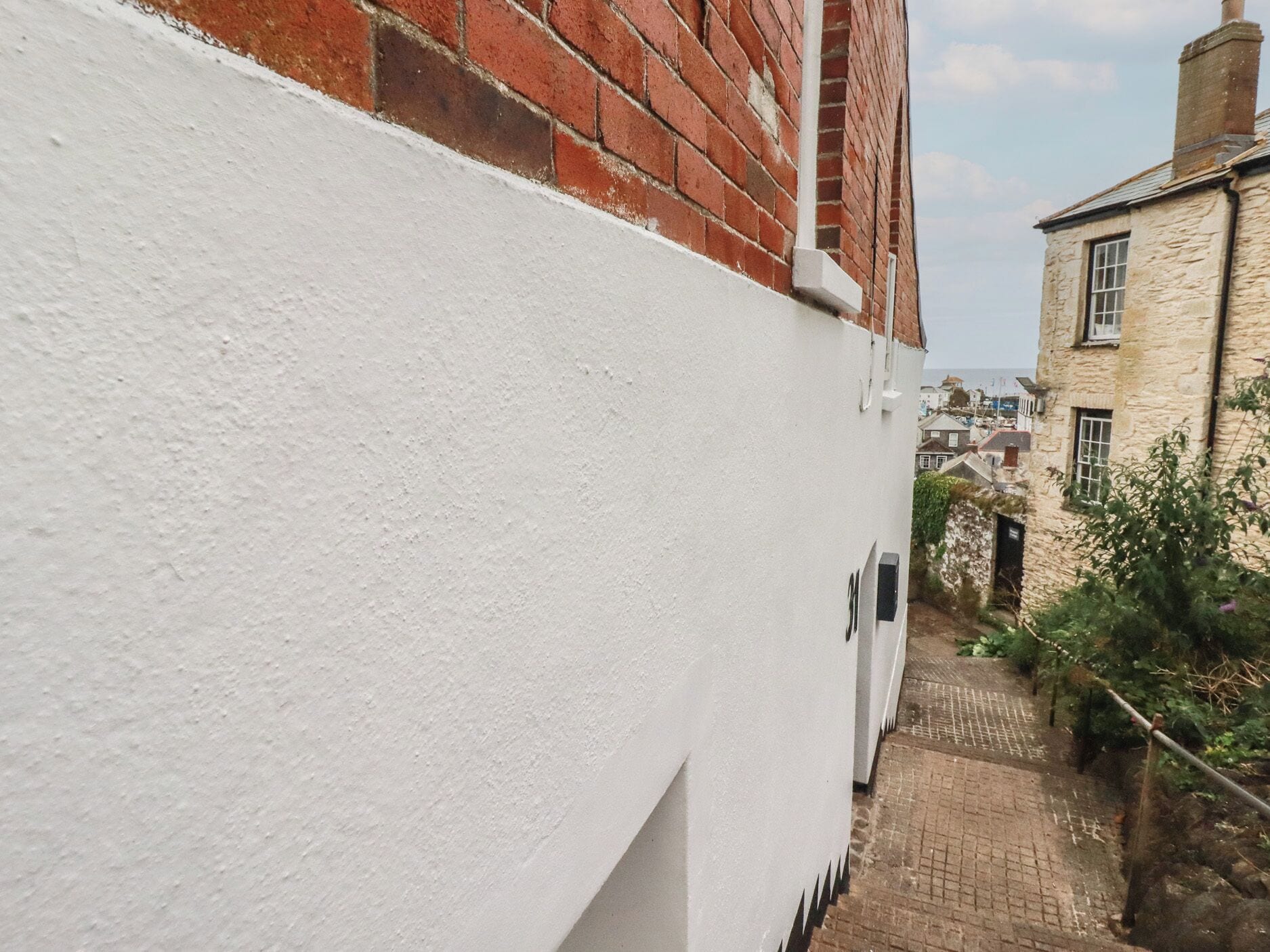 Un estrecho callejón con una pared blanca y un edificio de ladrillo en un lado.