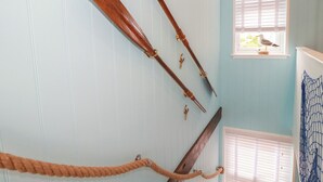 Una habitación con pared de madera, una barrera de cuerda y una ventana con un pájaro fuera.