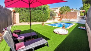 A backyard with artificial grass, a swimming pool, a red umbrella, and outdoor furniture. - VILLA JAVEA - TOSCAL (Javea)