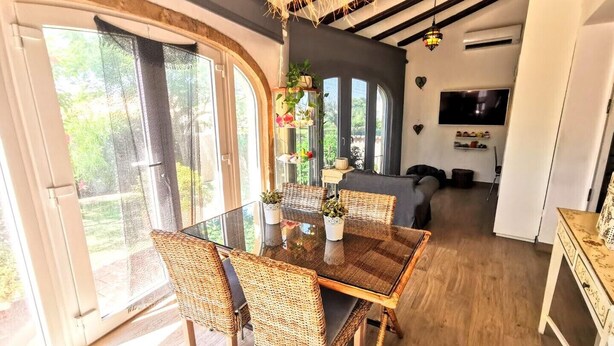 A dining area with a glass table, wicker chairs, and a view of greenery outside. - VILLA JAVEA - TOSCAL (Javea)