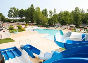 Ein Schwimmbecken mit Rutschen, Liegestühlen und einem kleinen Gebäude mit einem Kreuz.