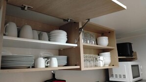 A kitchen with wooden shelves holding plates, cups, and glasses. - Mobile Home Near Chateau de Chaumont (Veuzain-sur-Loire)