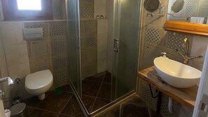 Une salle de bain avec une douche à parois de verre, des toilettes, un lavabo avec un miroir et des murs à motifs.