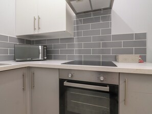 A kitchen with grey tiles, a microwave, an oven, and a toaster. - Luxury Winter Gardens Apartment 1 (Blackpool)