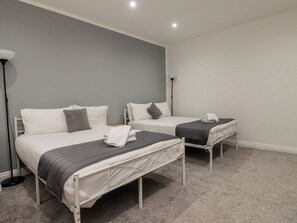 A hotel room with two beds, grey walls, and a carpeted floor. - Luxury Winter Gardens Apartment 1 (Blackpool)