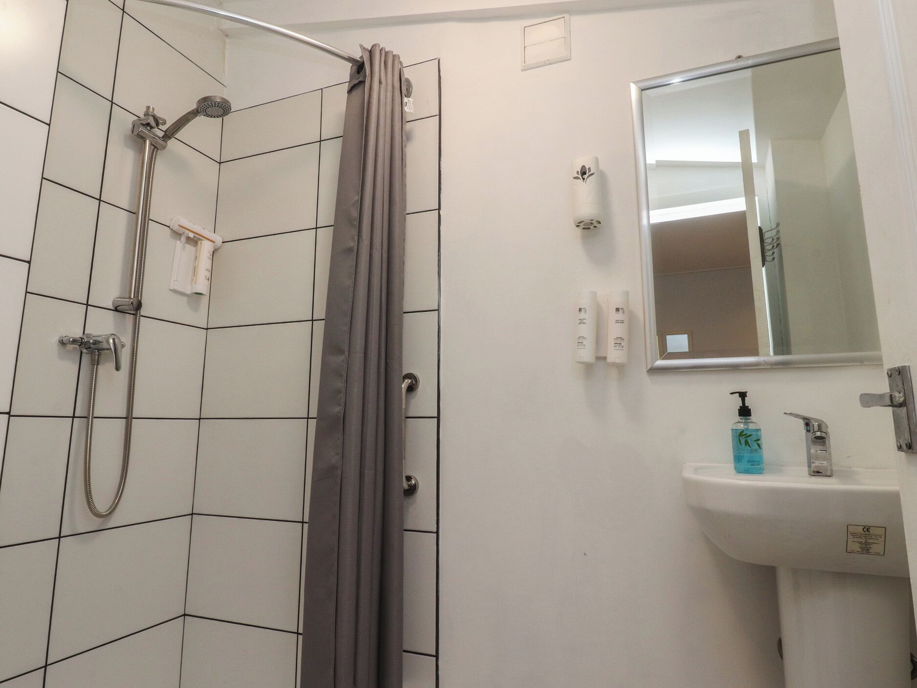 A bathroom with a shower, a sink, and a mirror.