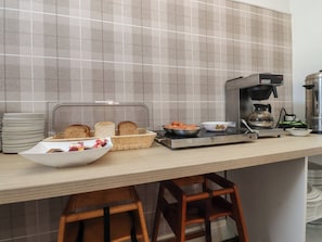 A kitchen with a coffee maker, a toaster, a bowl of fruit, and a basket of bread. - Luxury Winter Gardens Apartment 1 (Blackpool)