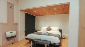 A bedroom with a bed, bedside tables, a wooden ceiling, and a wall-mounted hand dryer. - Luxury Winter Gardens Apartment 2 (Blackpool)