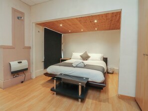 A bedroom with a bed, bedside tables, a wooden ceiling, and a wall-mounted hand dryer. - Luxury Winter Gardens Apartment 2 (Blackpool)