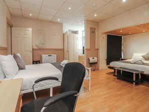 A hotel room with a bed, a chair, a desk, a washing machine, and a door. - Luxury Winter Gardens Apartment 2 (Blackpool)