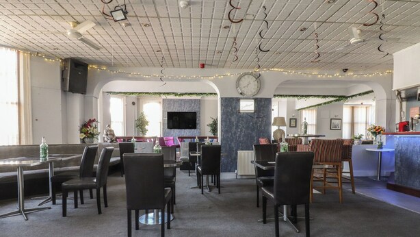 A spacious room with a dining area, a bar, and a television mounted on the wall. - Luxury Winter Gardens Apartment 2 (Blackpool)