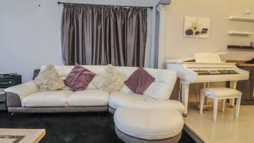 A living room with a white sofa, a piano, and a small table.