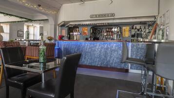 A bar area with a counter, bar stools, and a sign that reads 'LET THE WEEKEND BE-GIN'.