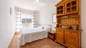 A bedroom with a bed, a wooden cabinet, a nightstand, and a window with curtains. - Almería Suite: Cathedral Penthouse (Almería)