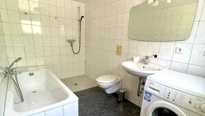 A bathroom with a bathtub, toilet, sink, and washing machine.