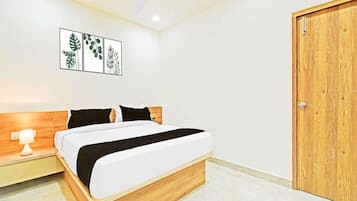 A bedroom with a bed, a nightstand, a ceiling fan, a wooden door, and wall art.