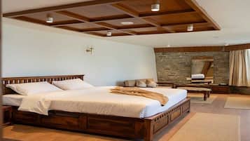 A spacious bedroom with a large bed, wooden headboard, and a stone wall.