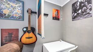 A room with a guitar, a white table, a chair, and various wall art. - Bright 1BR Flat w/ Free Parking & Easy City Access (Dublin)