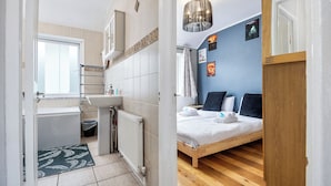 A compact room with a shower, sink, and a bed with pillows. - Bright 1BR Flat w/ Free Parking & Easy City Access (Dublin)