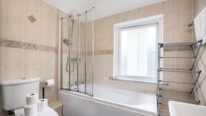 A bathroom with a bathtub, toilet, shower, and a window. - Bright 1BR Flat w/ Free Parking & Easy City Access (Dublin)