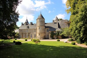 Um edifício grande e histórico com várias torres e um jardim bem cuidado.