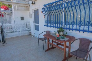 A patio with a table and chairs, a decorative blue metal fence, and a white wall. - Breeze - Seaside Serene Samos Getaway (Koumeika Samou)