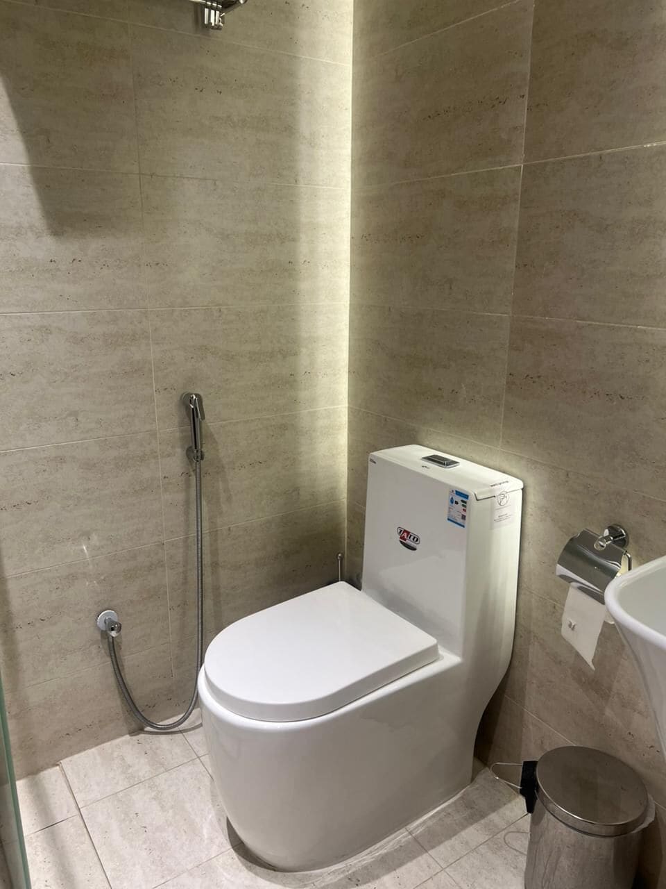 Een badkamer met een wit toilet, een douche en een wandgemonteerde boiler.
