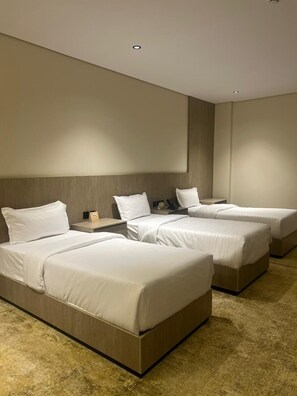 A hotel room with three beds, a wooden headboard, a flat-screen TV, and a carpeted floor. - Nasamat Silver Hotel (Madinah)